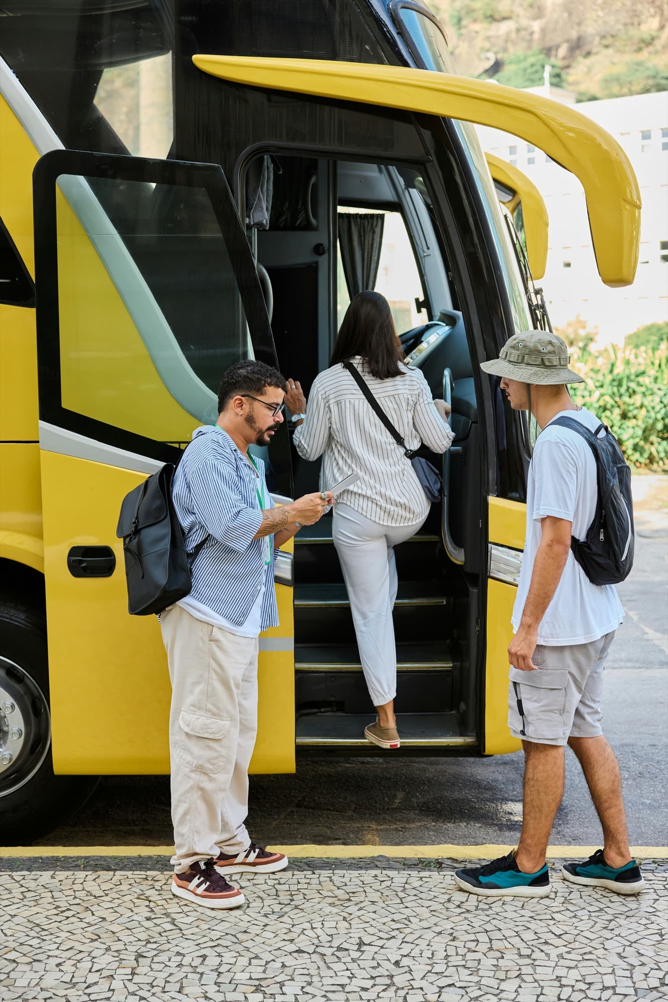 Reisende steigen mit Rucksäcken in einen Bus ein, ein Mann wartet an der Tür