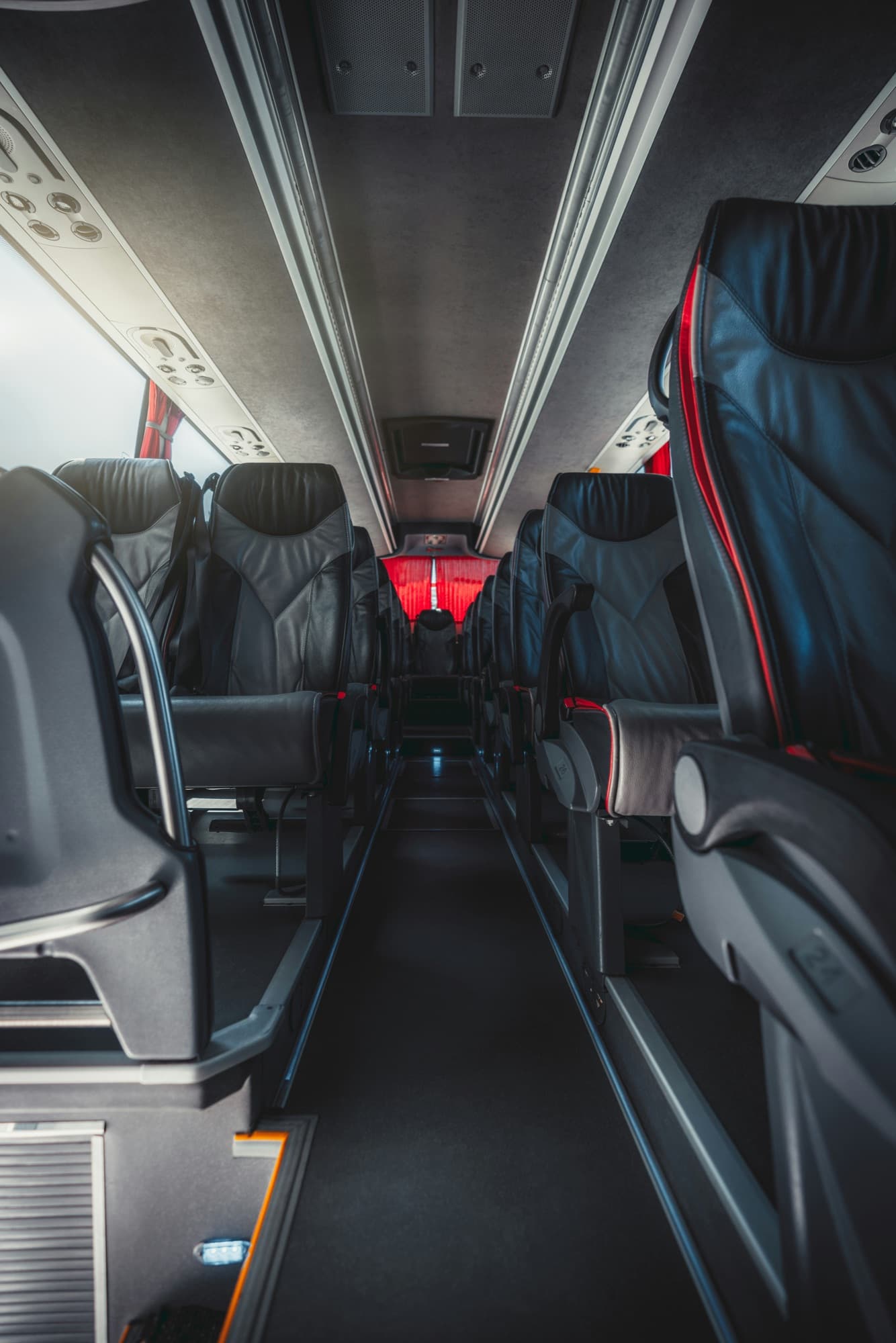 Mittelgang und Sitzreihen eines leeren Reisebusses mit dunklen Ledersitzen