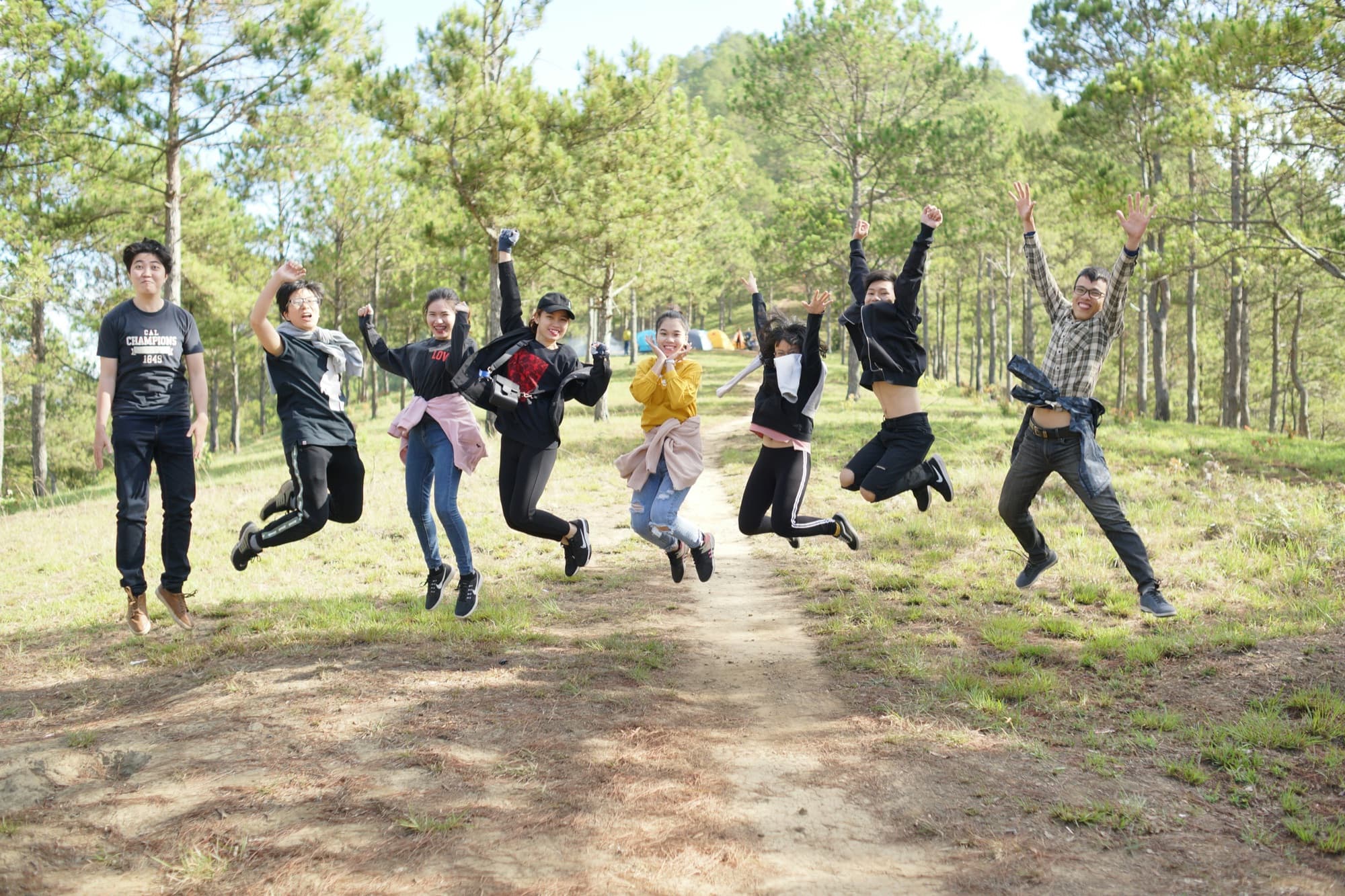 Eine Gruppe junger Leute springt gleichzeitig auf einem Waldweg in die Luft
