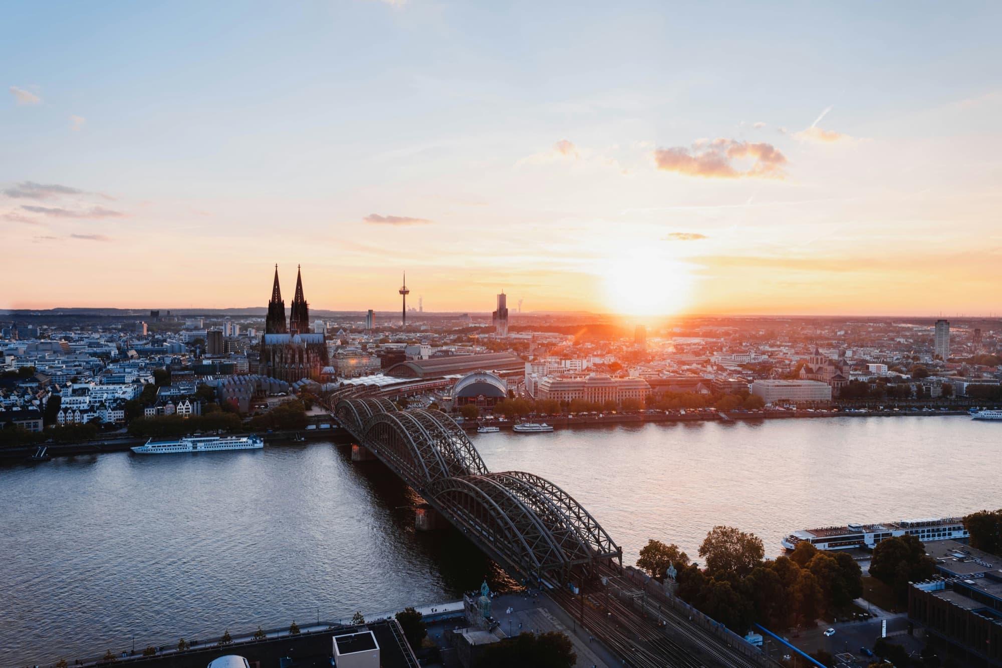 Blick über Köln mit Dom, Hohenzollernbrücke und Rhein bei Sonnenuntergang