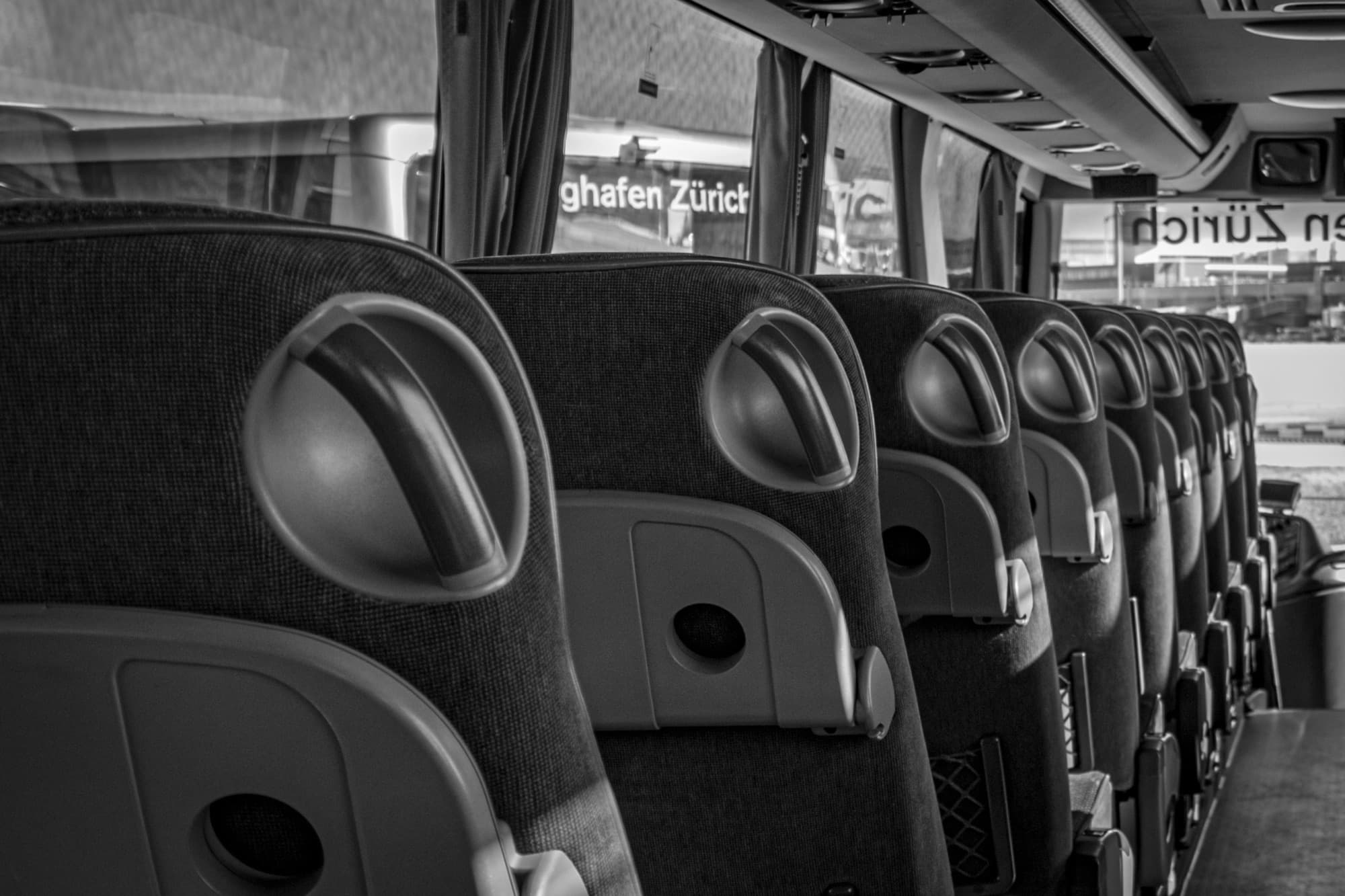 Sitzreihen in einem leeren Reisebus, Schwarzweißaufnahme